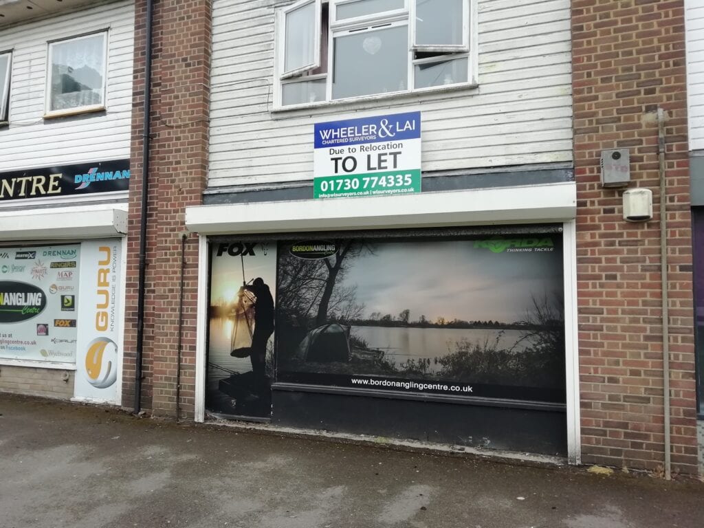 Shop front with Wheeler and Lai agency board to let in Bordon