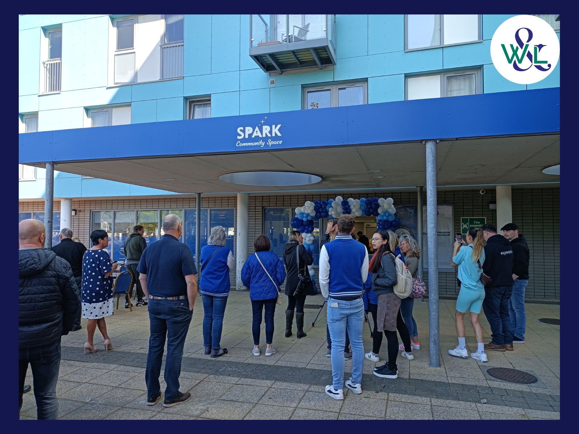 Outside a retail unit Spark Community Space, a crowd has gathered excited for the launch day. Moslty blue in aspect with the blue building and blue merchandise jackets that can be seen worn by some supporters.